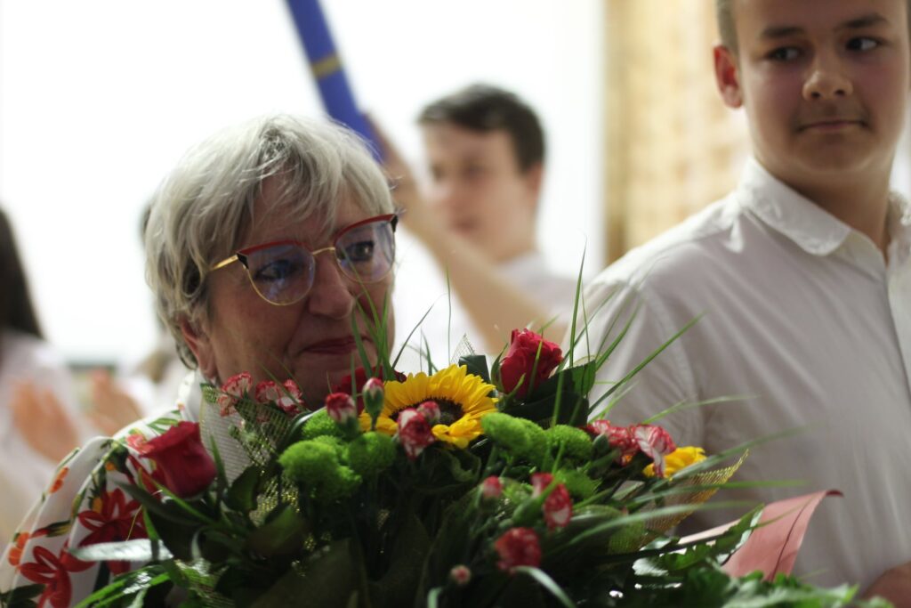 zbliżenie twarzy Pani Dyrektor z kwiatami