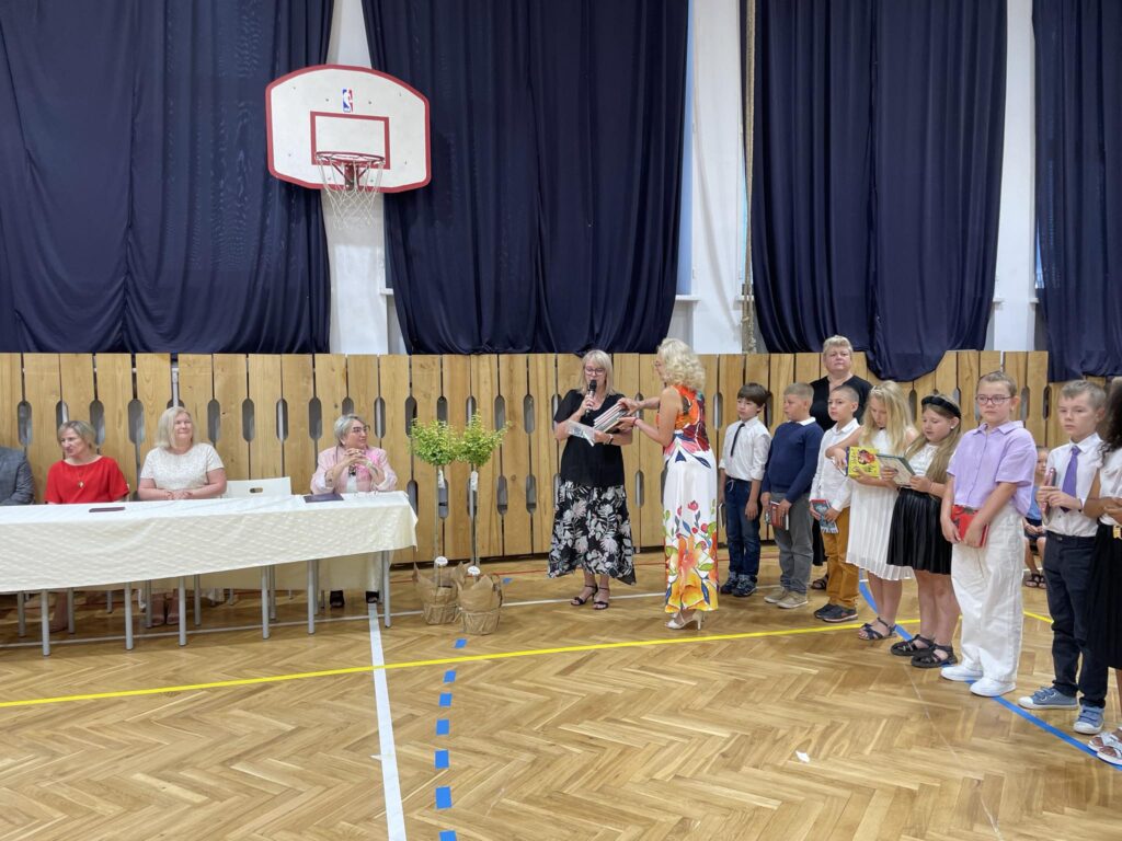 grupa uczniów ma wręczane nagrody na środku sali gimnastycznej