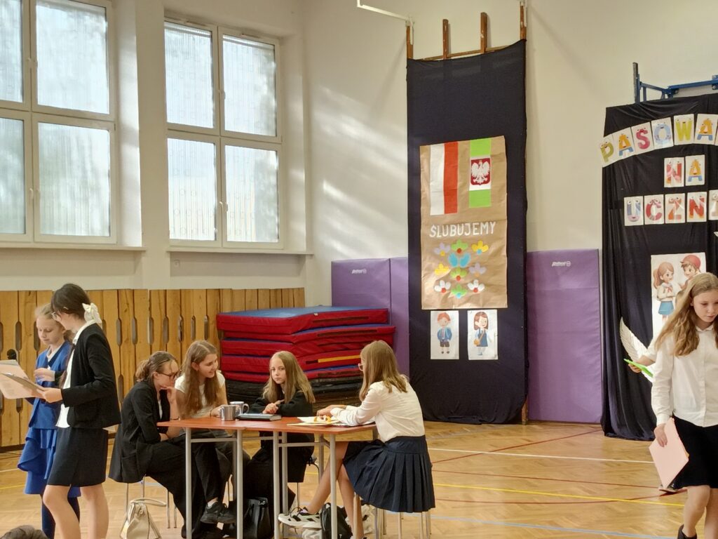 Uczennice omawiające historię święta, w tle uczennice przy stole.