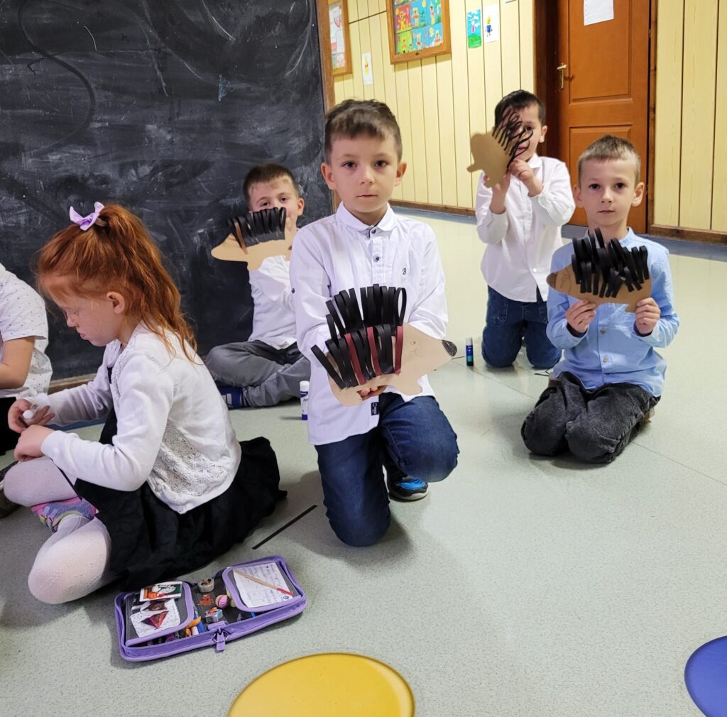 dzieci na zdjęciu prezentują wykonane przez siebie jeże z papieru