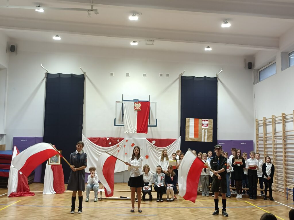 uczniowie machaj biało-czerwonymi flagami podczas pieśni