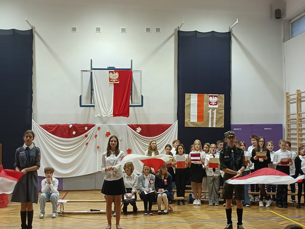 uczniowie machaj biało-czerwonymi flagami podczas pieśni