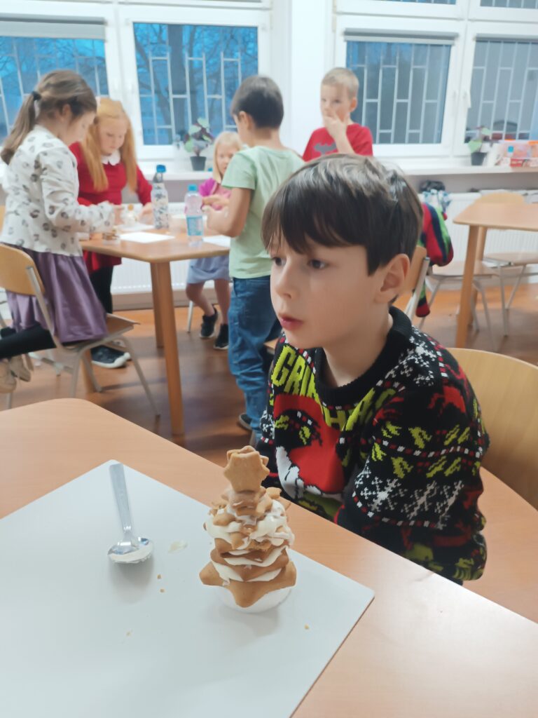 chłopiec siedzi przed choinką z piernika