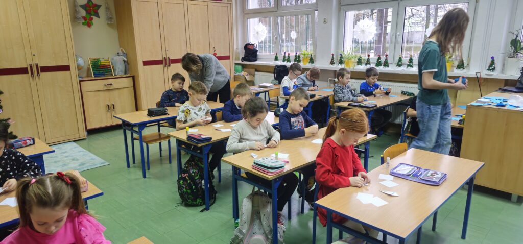 Na zdjęciu grupa dzieci składająca gwiazdy origami