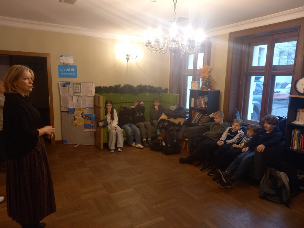 dzieci siedzą na kanapach, pani im coś tłumaczy