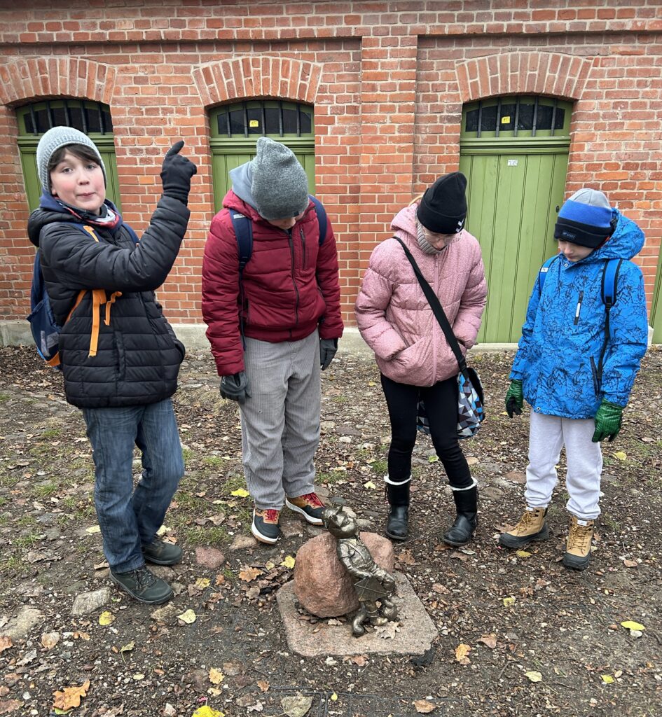 chłopcy na zdjęciu przed małą rzeźbą