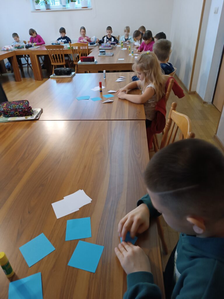 Na zdjęciu grupa dzieci składająca gwiazdy origami
