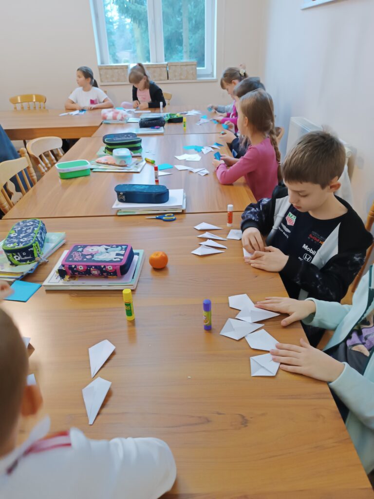 Na zdjęciu grupa dzieci składająca gwiazdy.