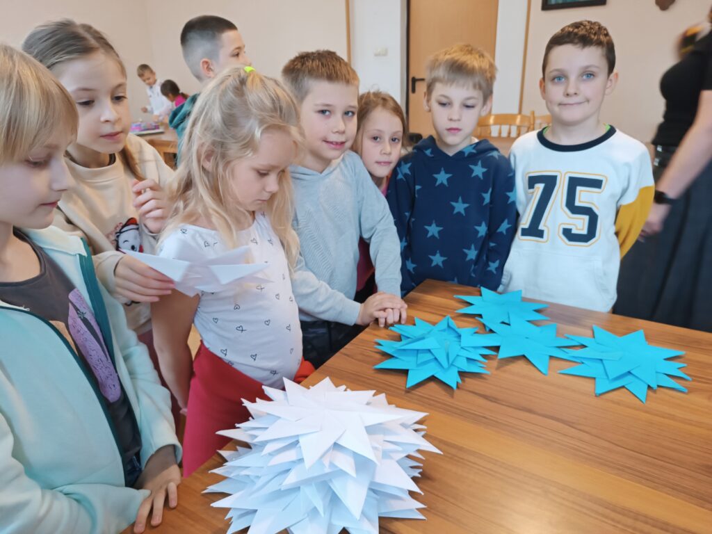 Na zdjęciu grupa dzieci składająca gwiazdy.