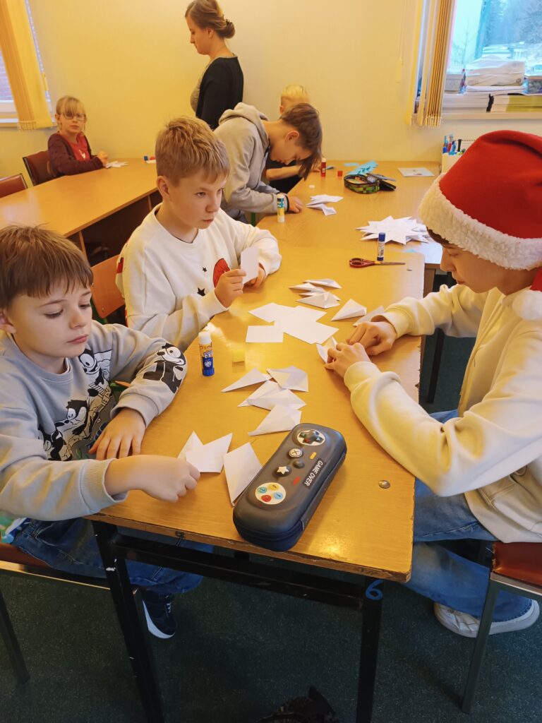 Na zdjęciu grupa dzieci składająca gwiazdy.