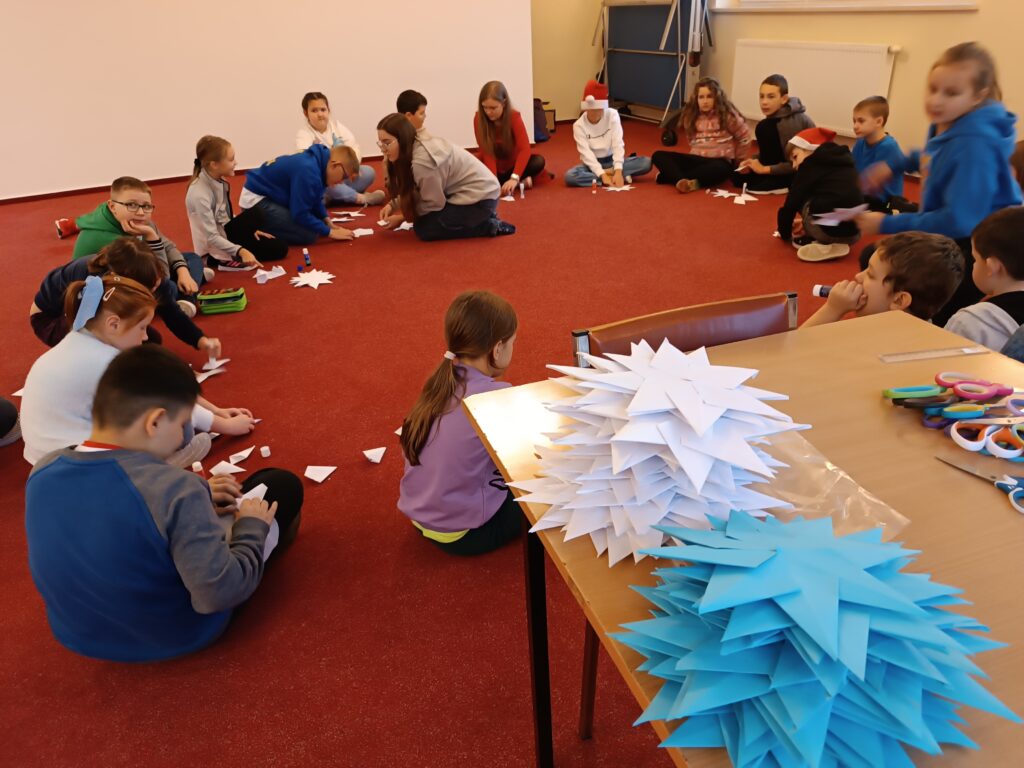 Na zdjęciu grupa dzieci składająca gwiazdy origami