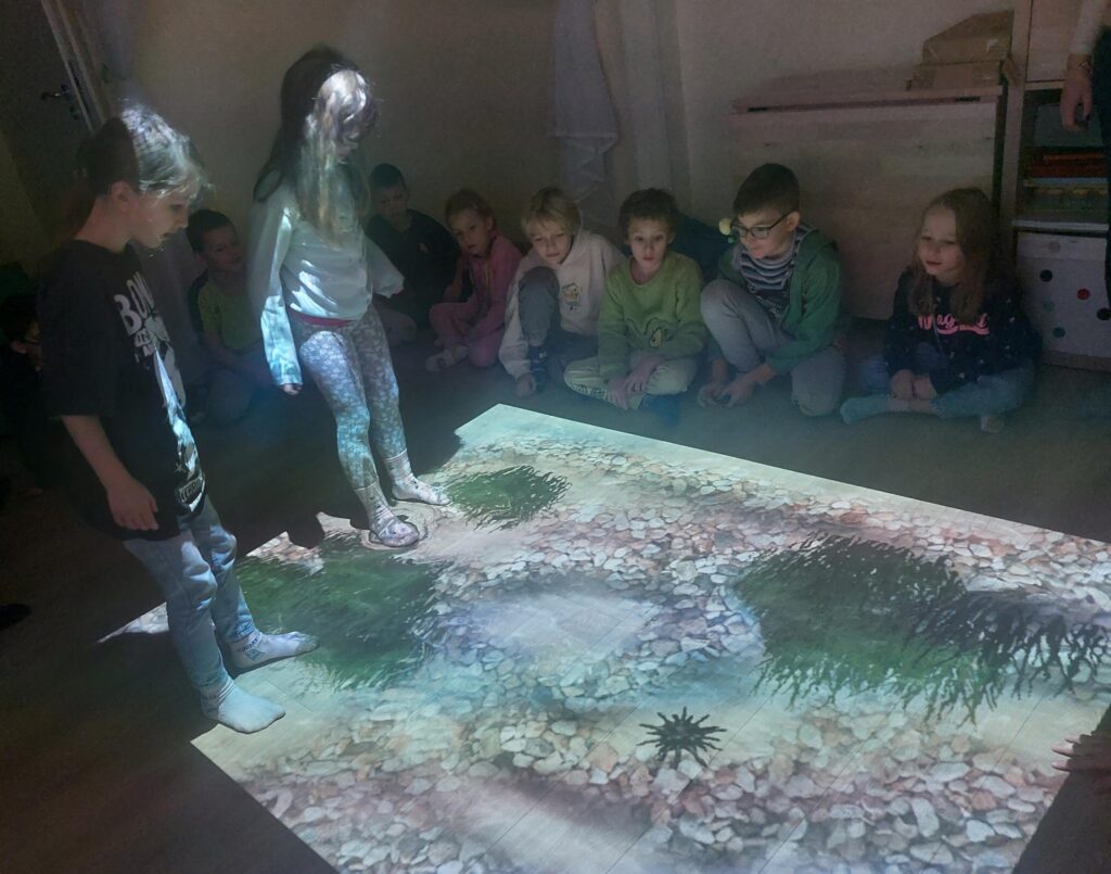 dzieci korzystają z dywanu interaktywnego