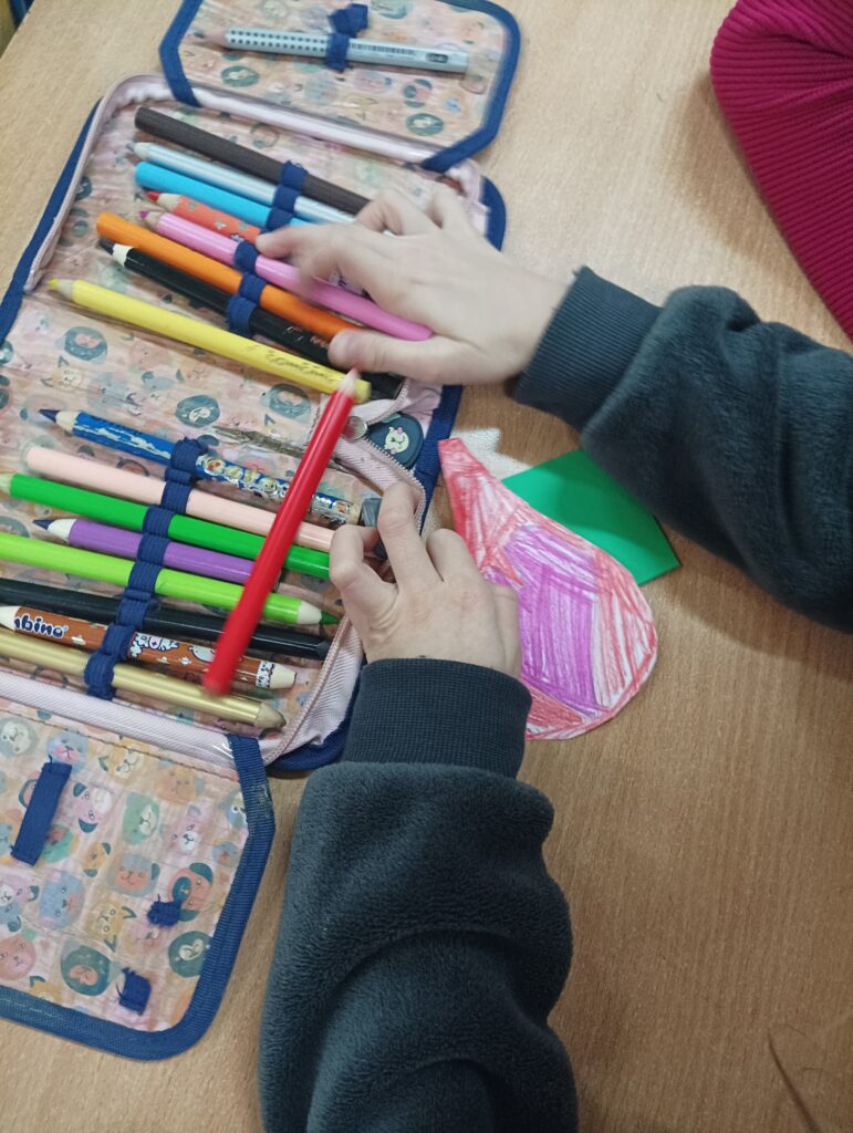 ręce dziecka wyciągają kolorowe pisaki z piórnika