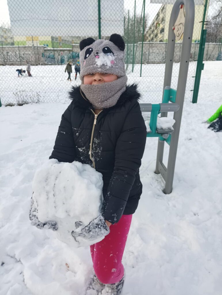 dziecko trzyma kulę śniegu w rękach