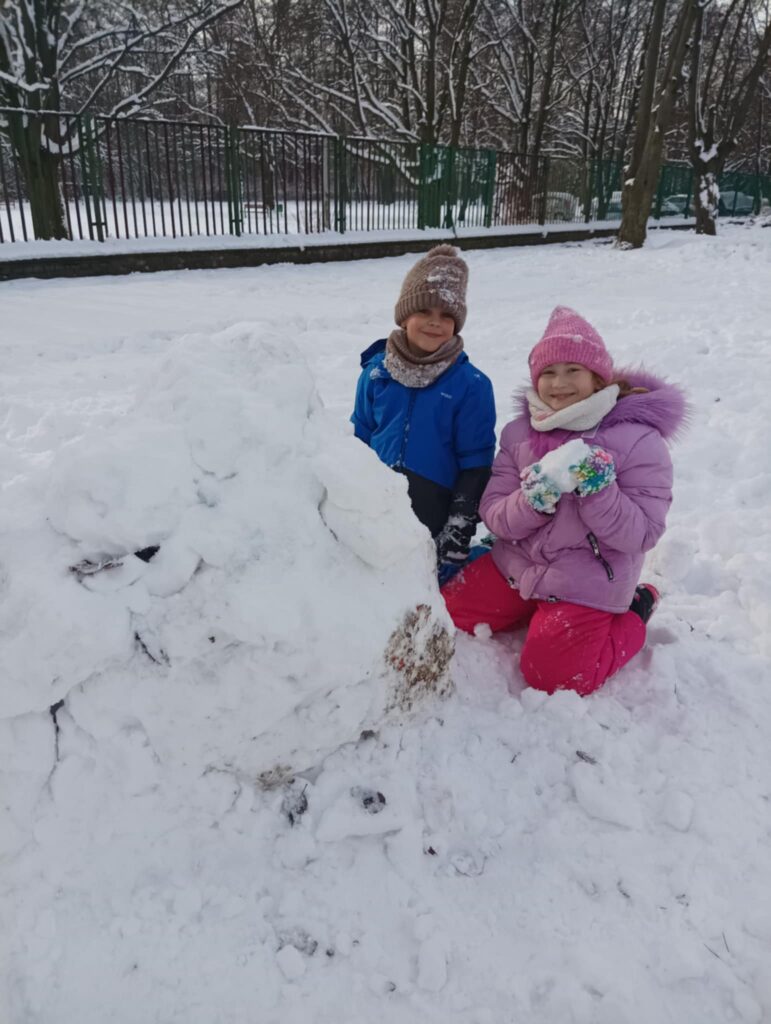 dwoje dzieci robi kulę śnieżną
