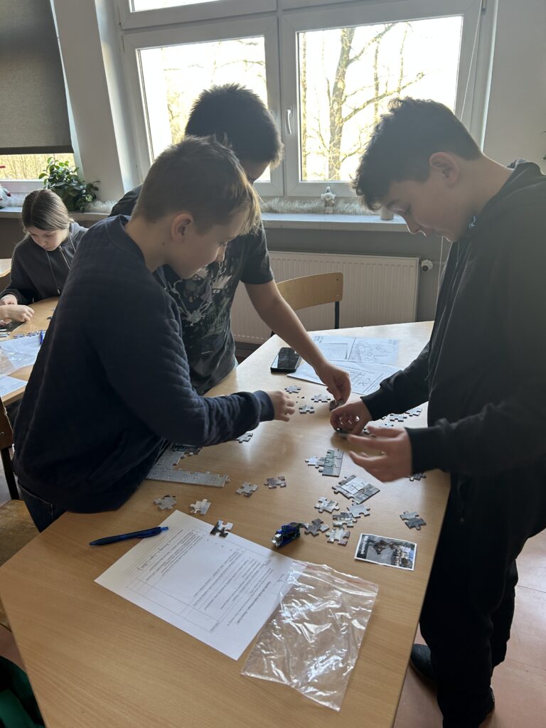 chłopcy stoją przy ławce i układają puzzle