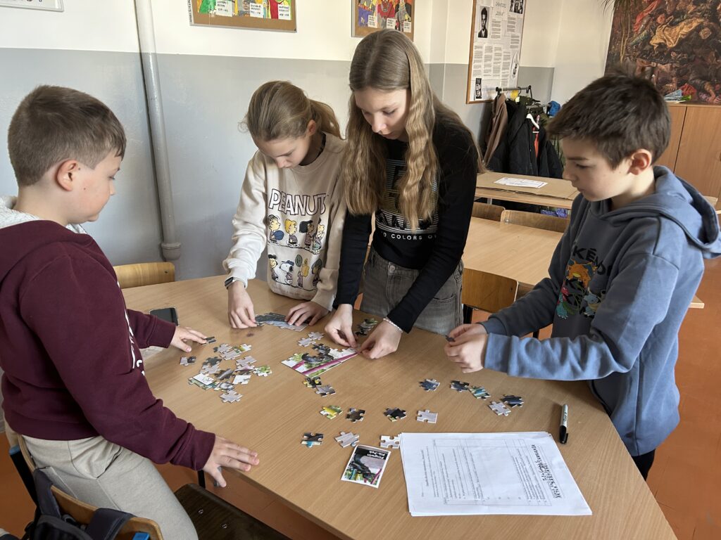dzieci stoją przy ławkach i układają puzzle