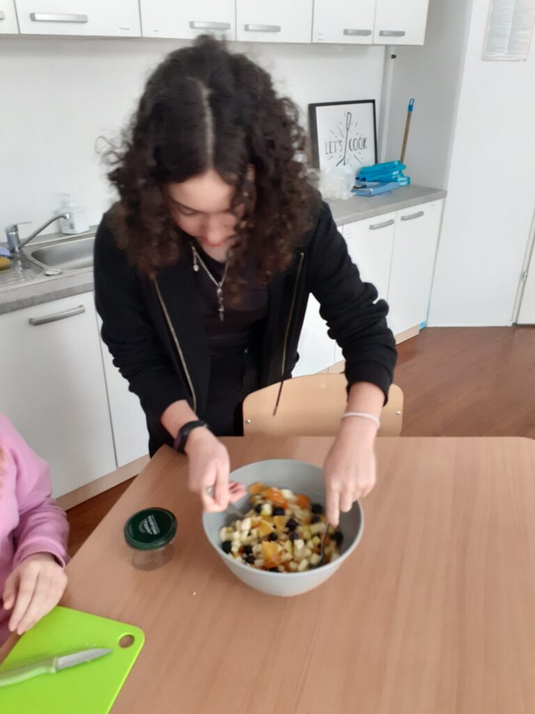 na zdjęciu widzimy uczennicę mieszającą składniki na sałatkę w misce.