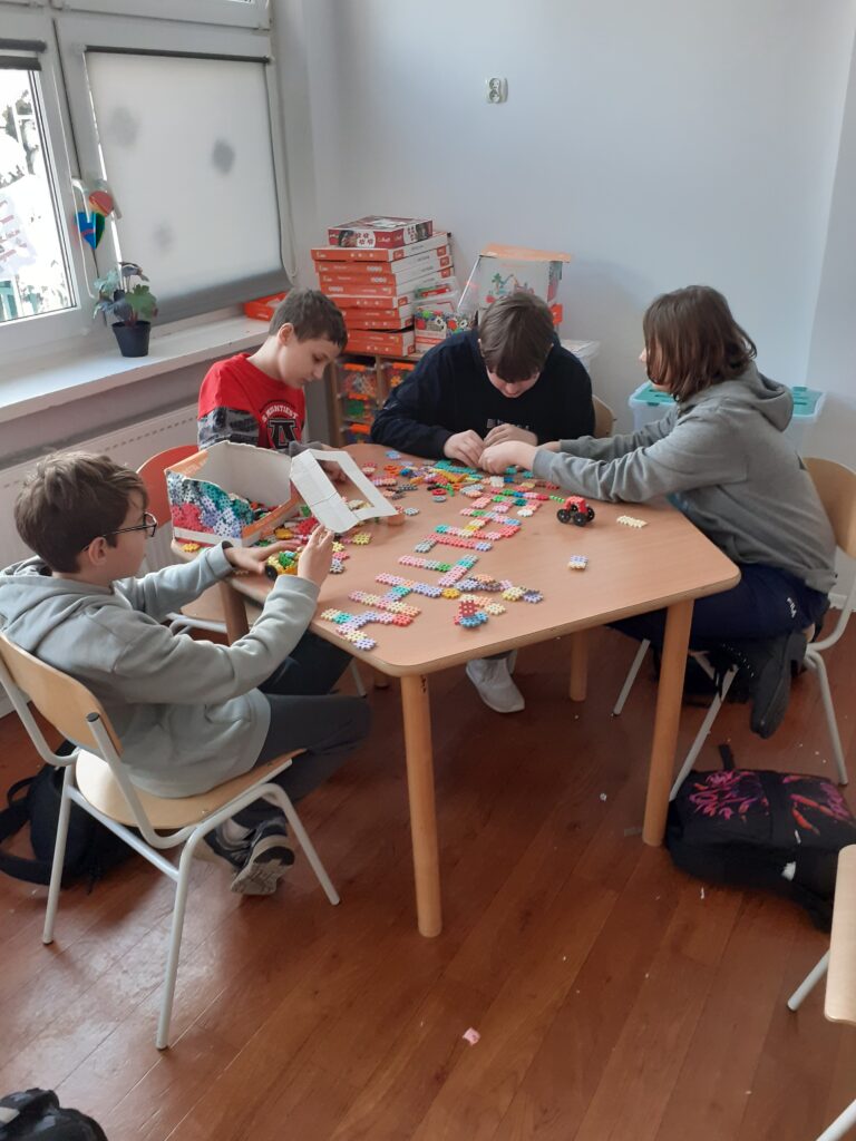 na zdjęciu widzimy uczniów układających napis z puzzli.