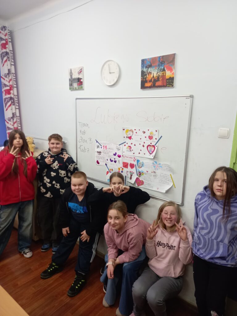 uczniowie stoją przy powieszonych pracach