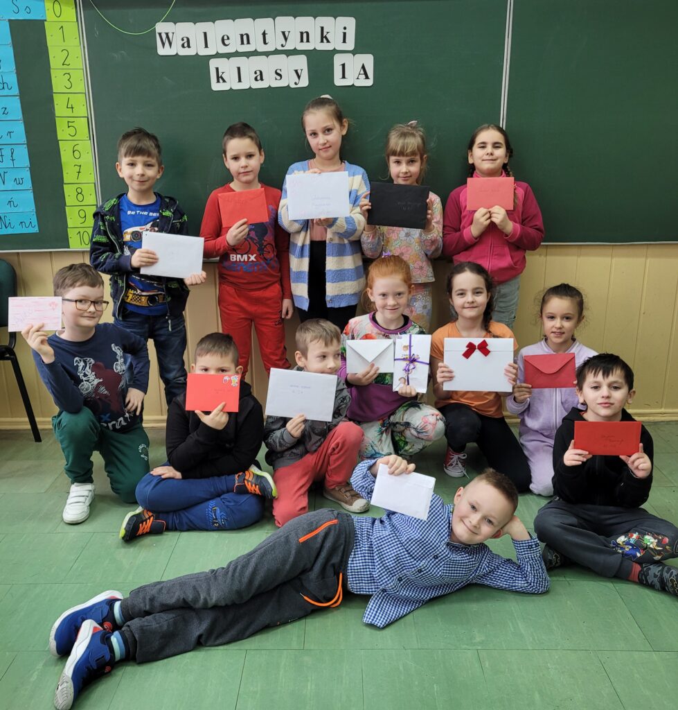 zdjęcie grupowe uczniów na tle ściany z napisem Walentynki klasy 1a