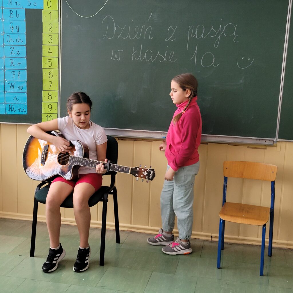 jedna dziewczynka śpiewa druga akompaniuje na gitarze