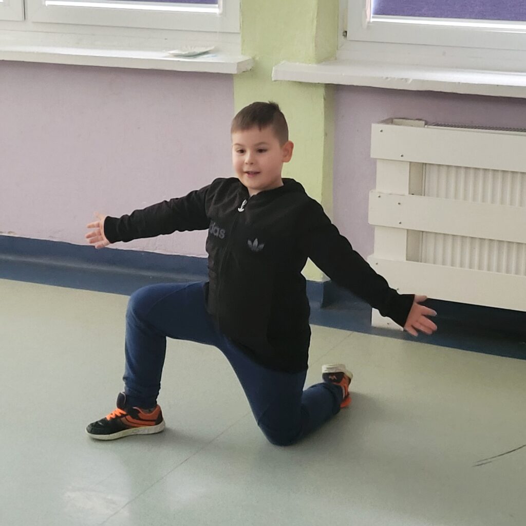 uczeń uklęknął na jedno kolanko i rozkłada ręce jak by w trakcie tańca