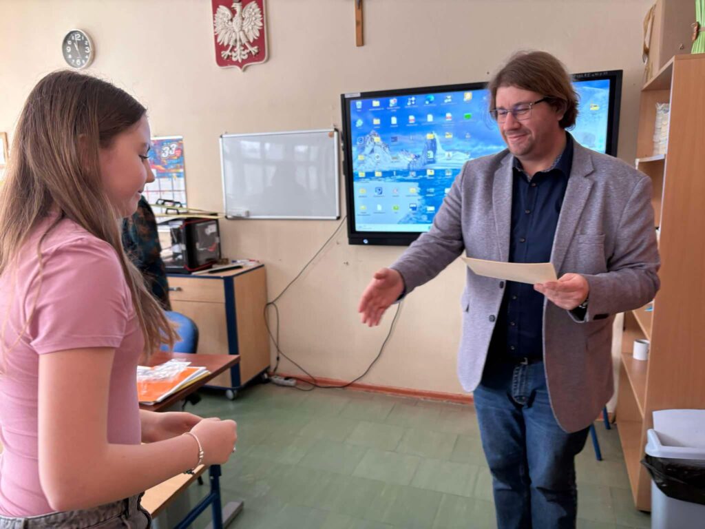 uczennica odbiera nagrodę z dyplomem