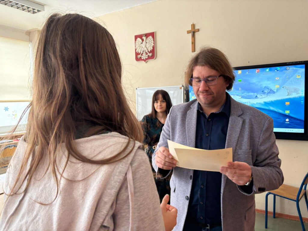 uczennica odbiera nagrodę z dyplomem