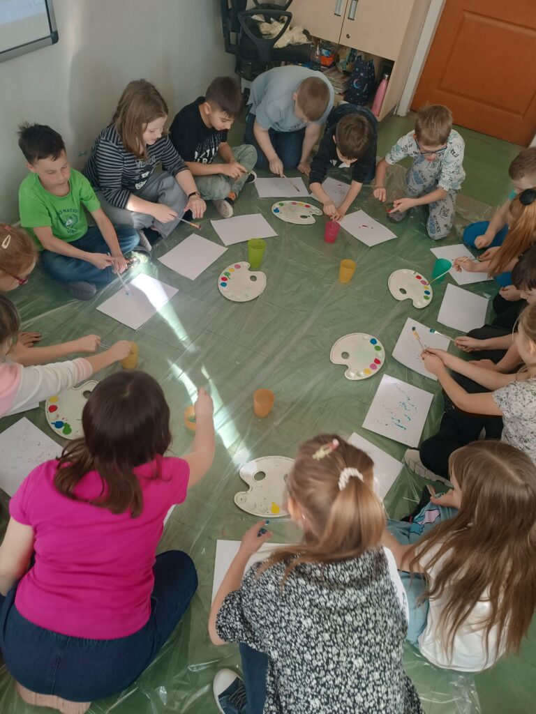 Na zdjęciu działania plastyczne dzieci które przy pomocy pędzla i farby tworzą nakrapiany papier artystyczny.