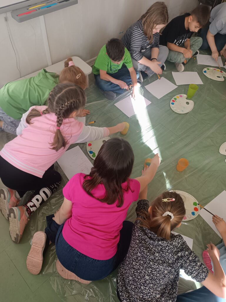 Na zdjęciu działania plastyczne dzieci które przy pomocy pędzla i farby tworzą nakrapiany papier artystyczny.