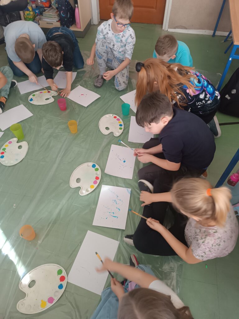 Na zdjęciu działania plastyczne dzieci które przy pomocy pędzla i farby tworzą nakrapiany papier artystyczny.
