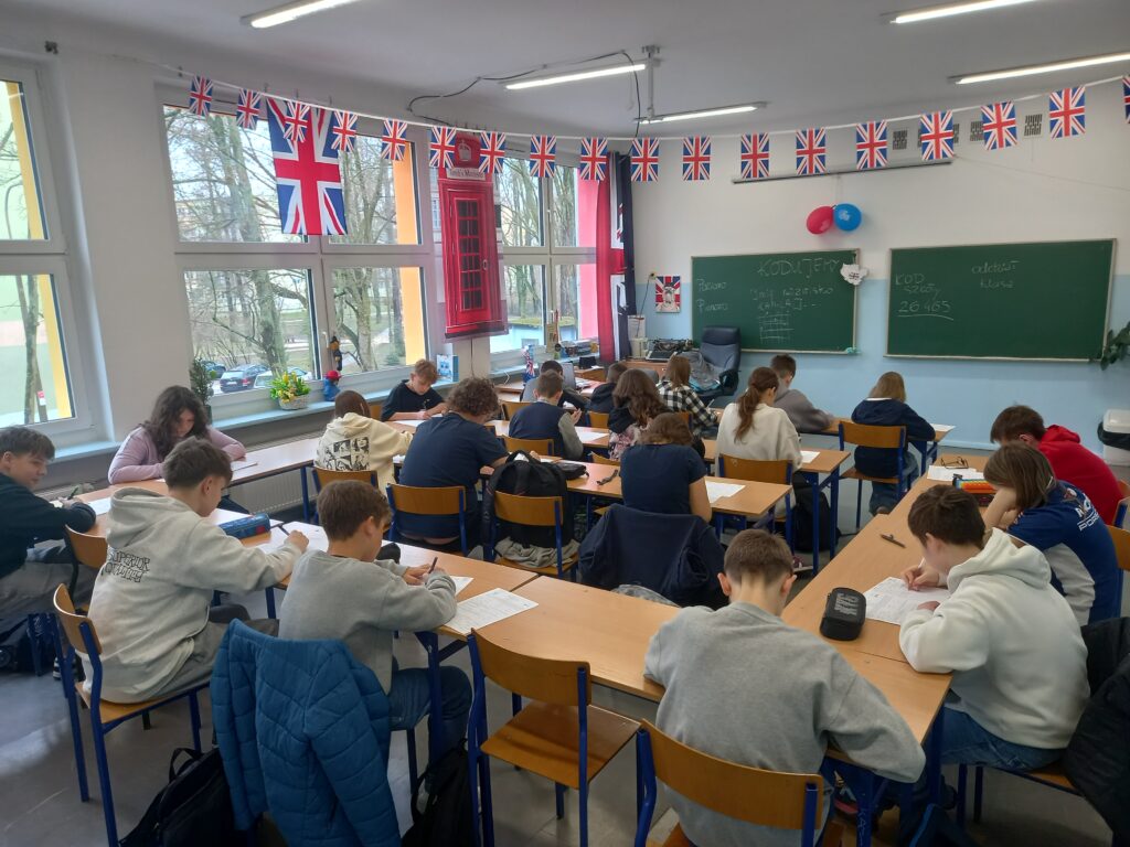 zdjęcie grupowe uczniów siedzących w ławkach przy testach.