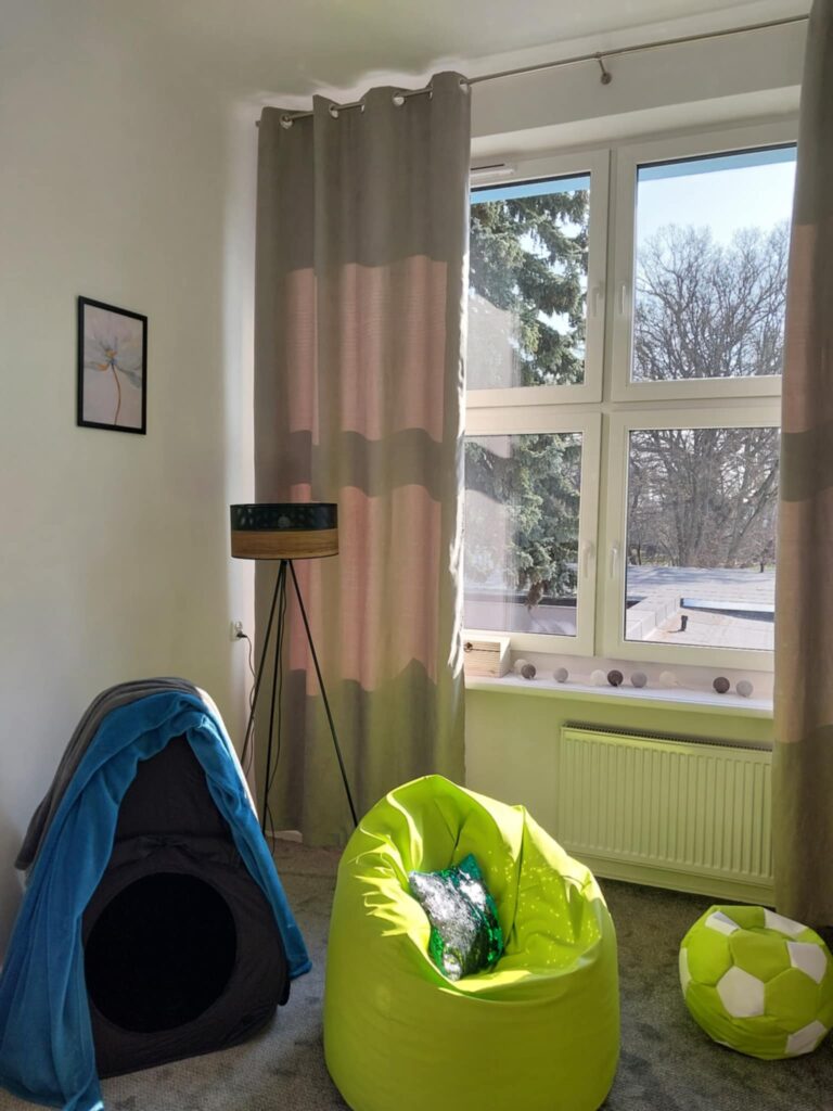 na zdjęciu kolorowe pufy i stonowane zasłony
