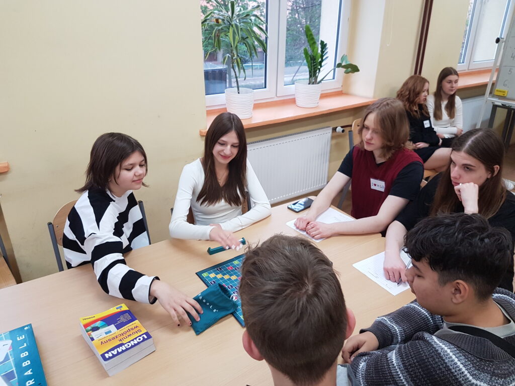 uczennice podczas gry w scrable siedzą przy ławce, przeciwnicy to grupa chłopców