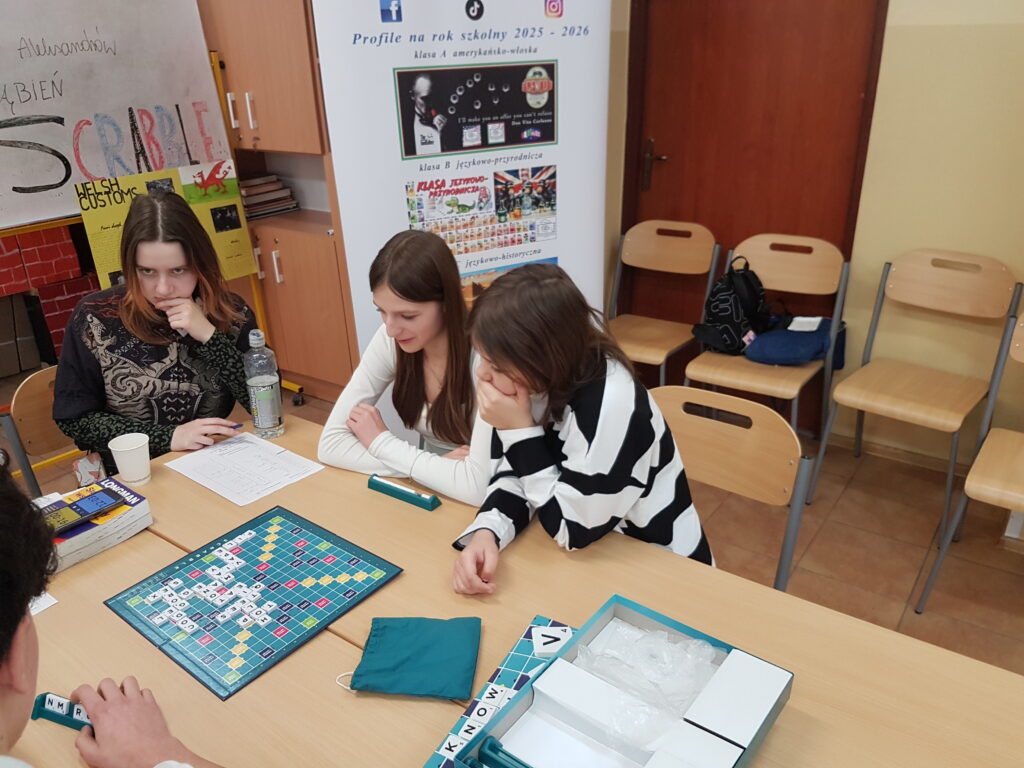 uczennice podczas gry w scrable siedzą przy ławce, przeciwnicy to grupa chłopców