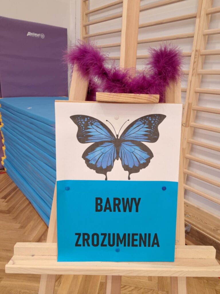 również namalowany niebieski motyl pod nim napis na niebieskim tle barwy zrozumienia