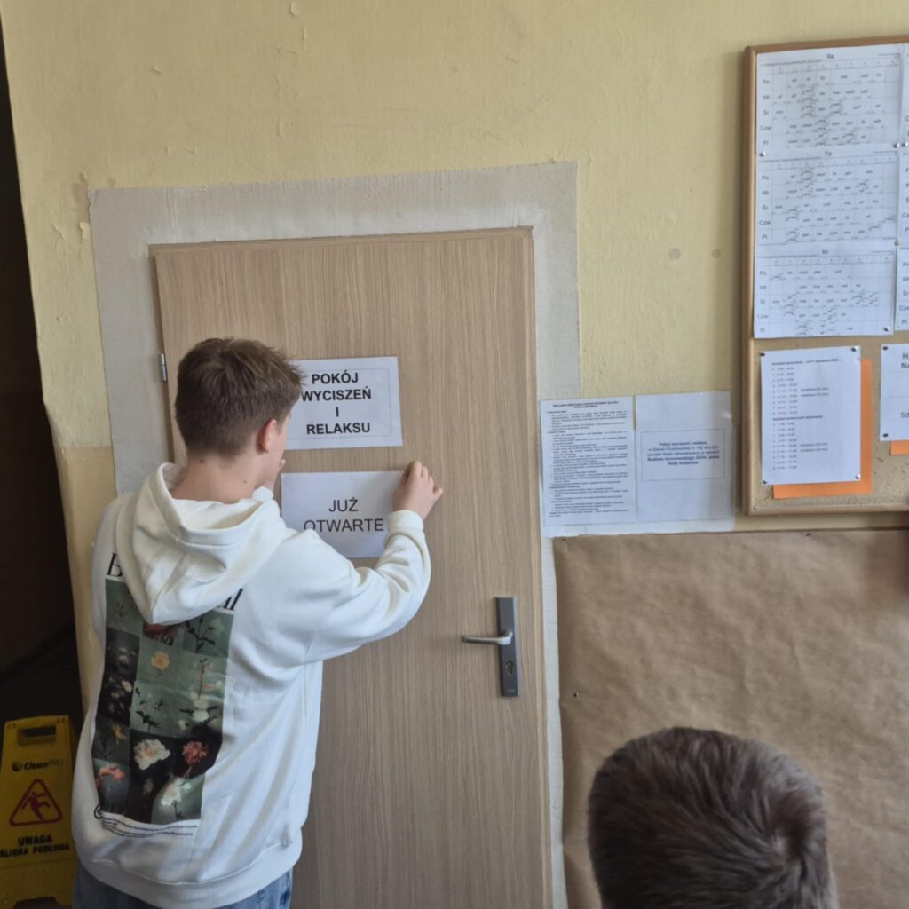 uczeń nakleja na drzwi kartkę już otwarte