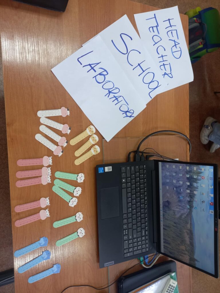 Biurko z laptopem, kartkami z napisami po angielsku i kolorowymi patyczkami