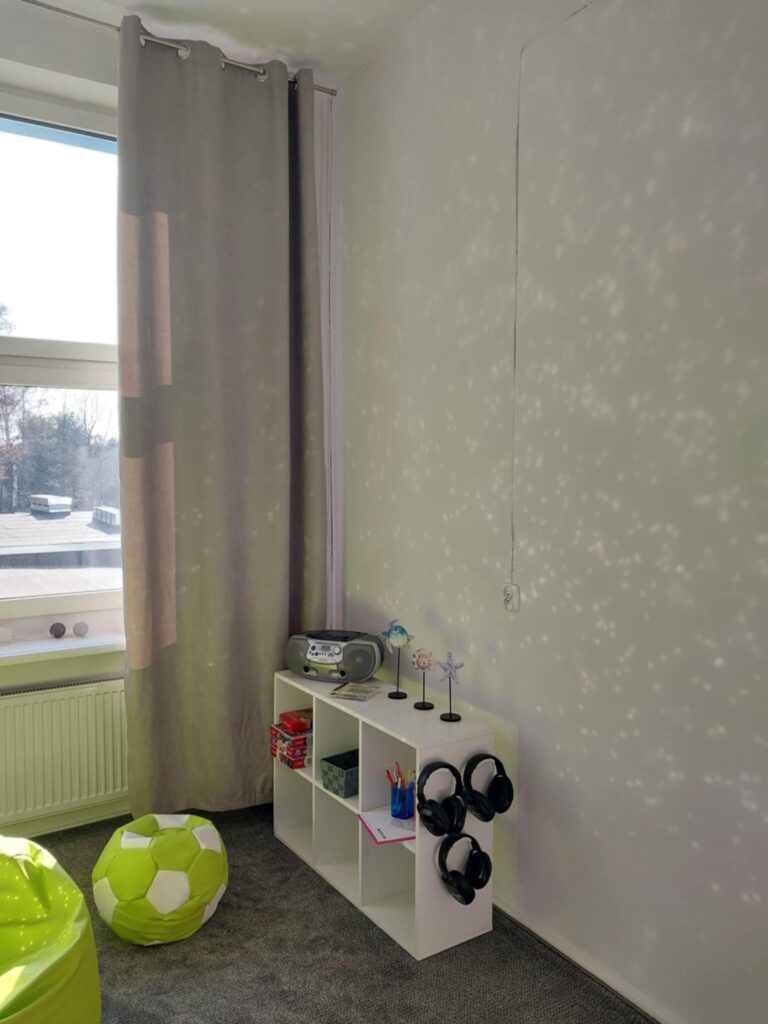 Na zdjęciu widać pokój wyciszeń z małym regałem i wiszącymi na nim słuchawkami wyciszającymi