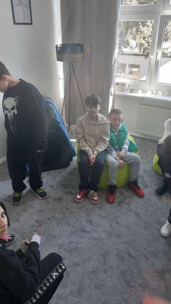 dzieci siedzą na pufach w pokoju