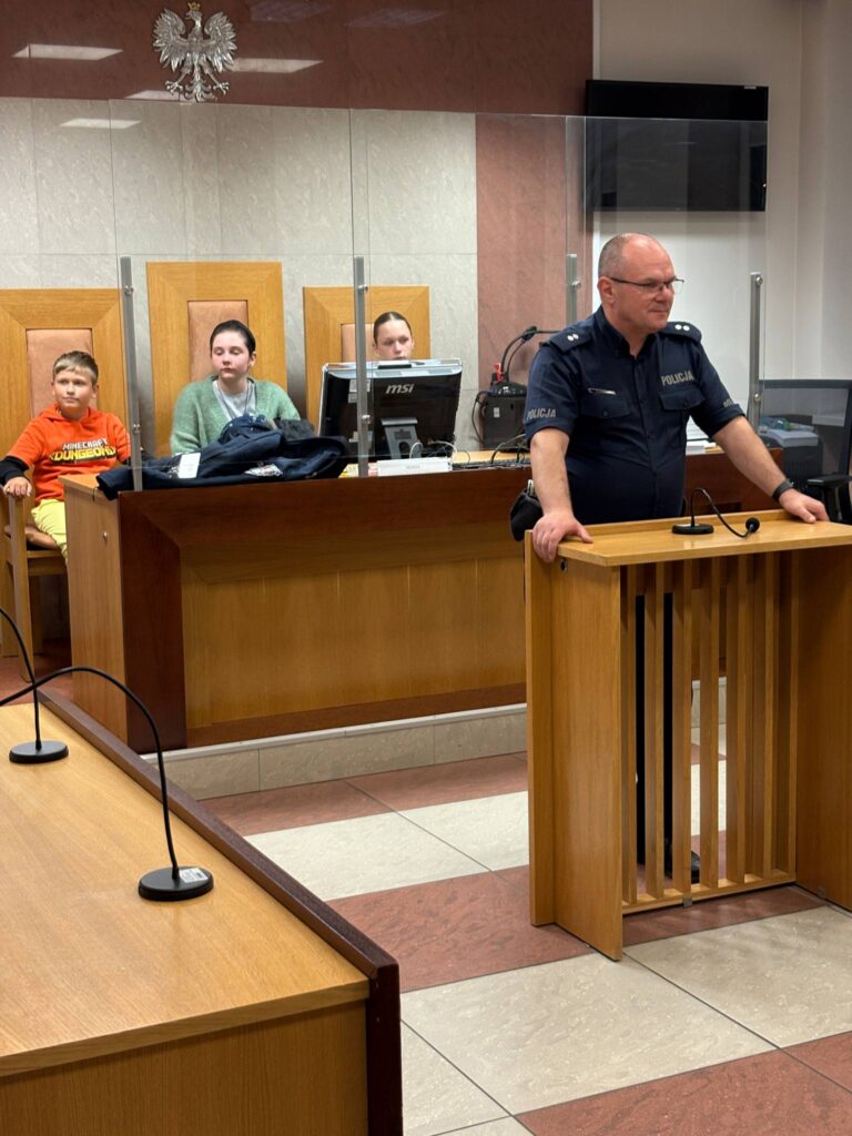 policjant przeprowadza przebieg sądowy z dziećmi