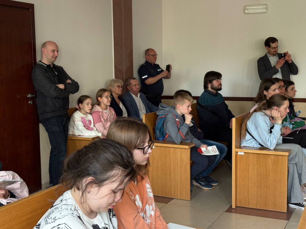 dzieci słuchają sędzi siedząc w ławkach 