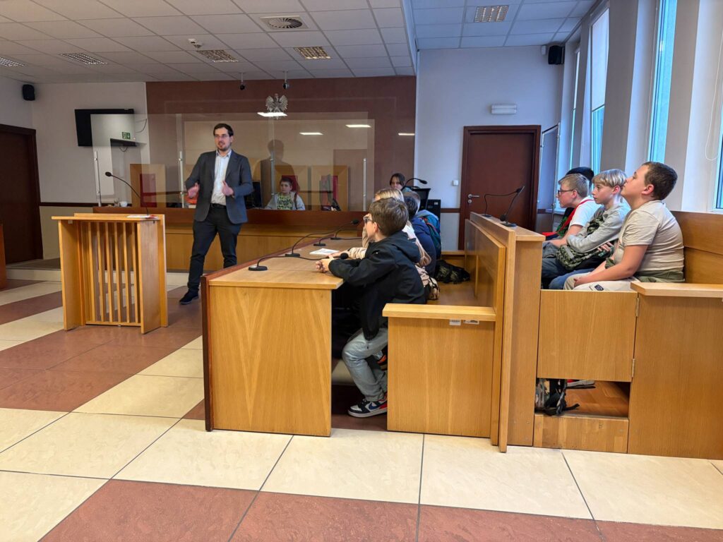 pracownik sądu opowiada uczniom o przepisach, uczniowie siedzą w ławach