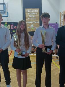 dwoje uczniów trzyma tarcze i puchary