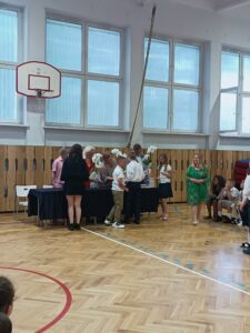 uczniowie wręczają kwiaty storczyki- dyrektorom.