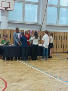 uczniowie wręczają kwiaty storczyki- dyrektorom.