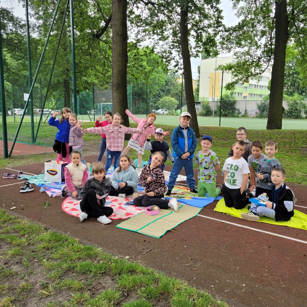 zdjęcie grupowe dzieci, siedzą na kocykach.