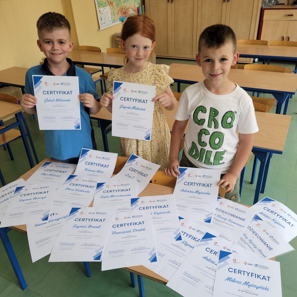 troje uczniów prezentuje z uśmiechem certyfikaty dla klasyc