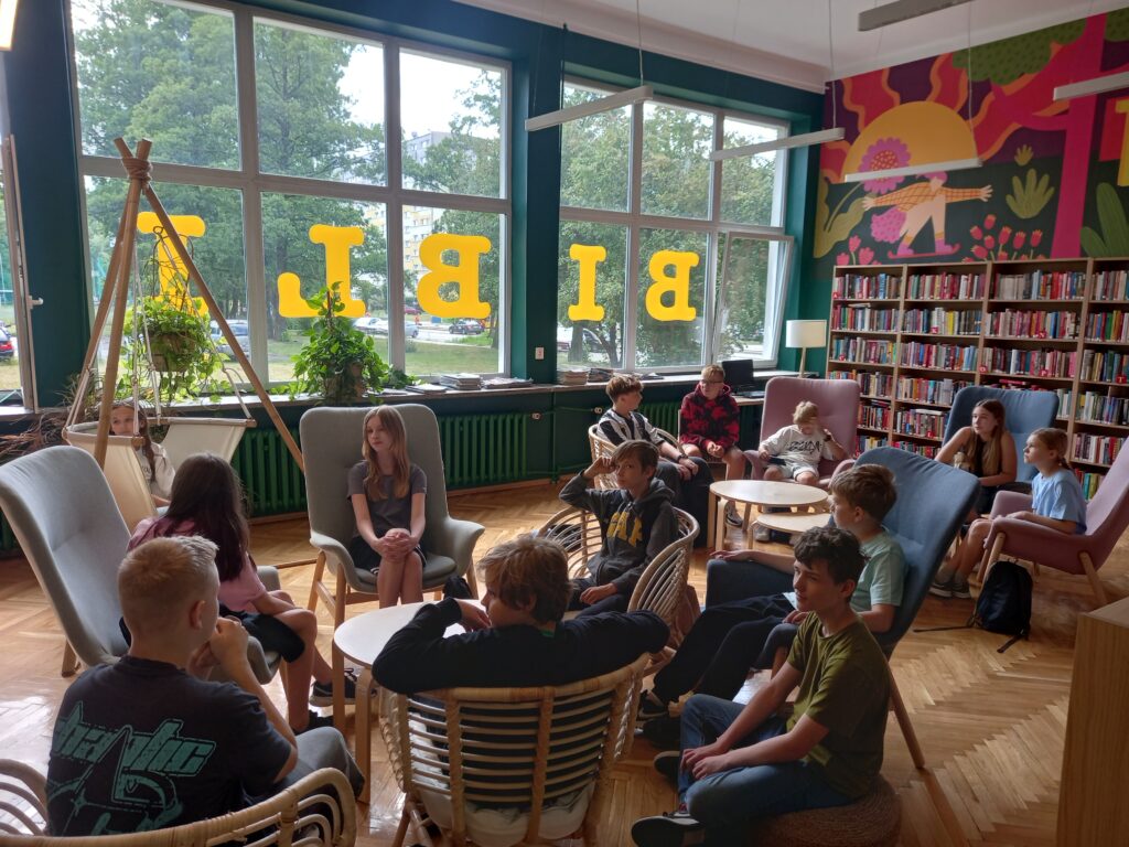 uczniowie siedzą w fotelach w bibliotece